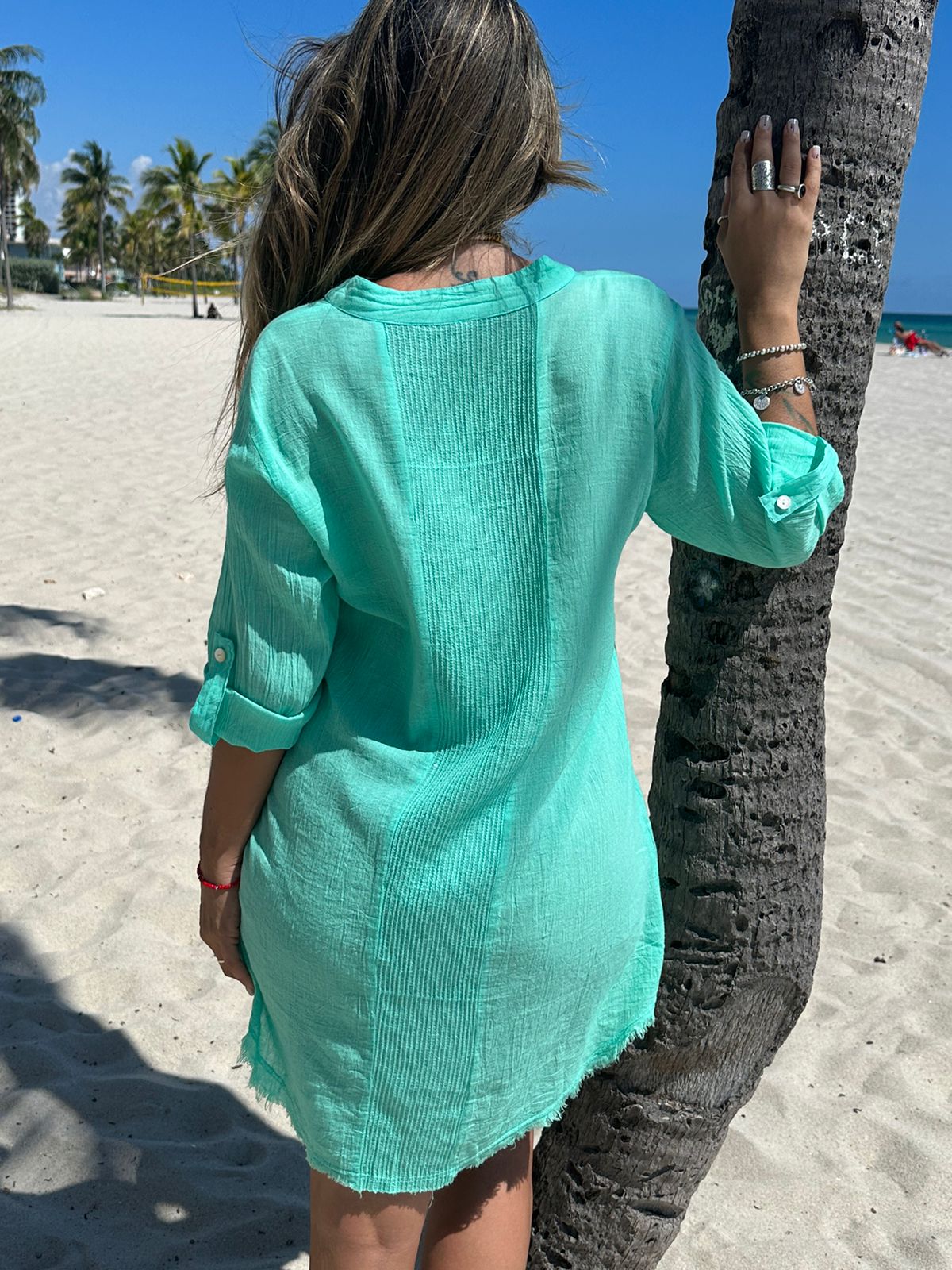 Back view of model wearing short green cotton shirt dress with sequins detail, beachwear style