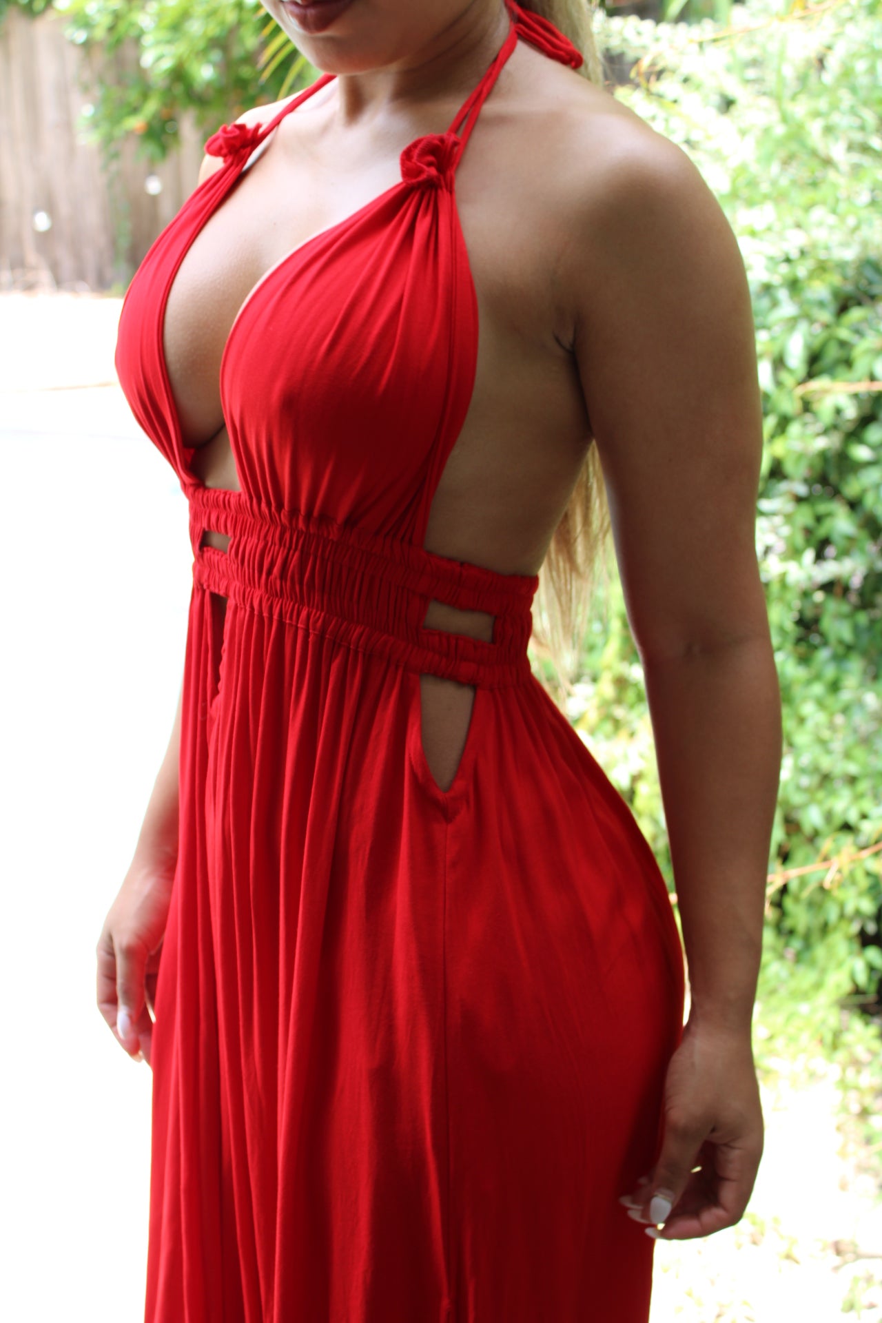 side view of model wearing long red rayon halter dress with deep neckline, elastic waist and tie at the neck