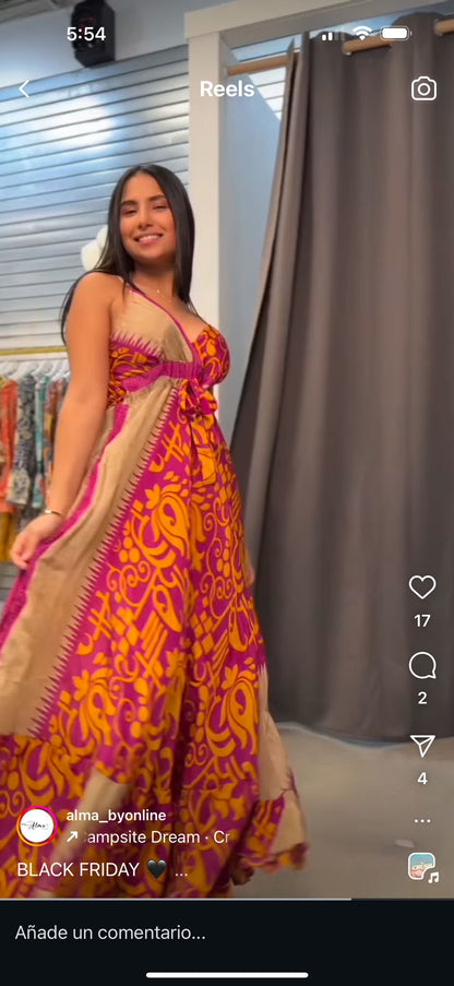 Model indoors wearing the Alma Dress in red and orange multicolor, a maxi dress with front tie, one size