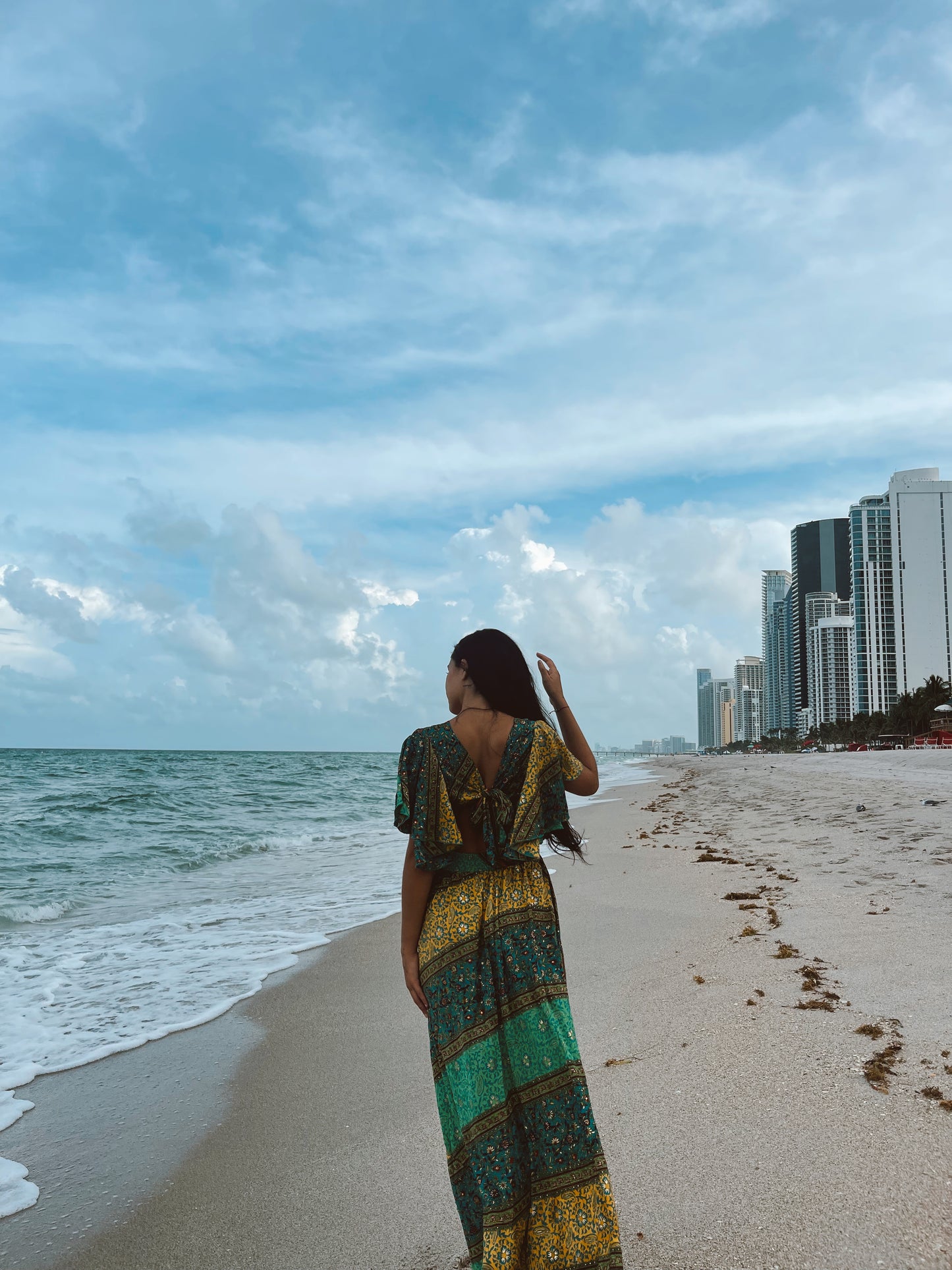 woman on the beach wearing a long multicolor dress with deep V- neckline and tied back
