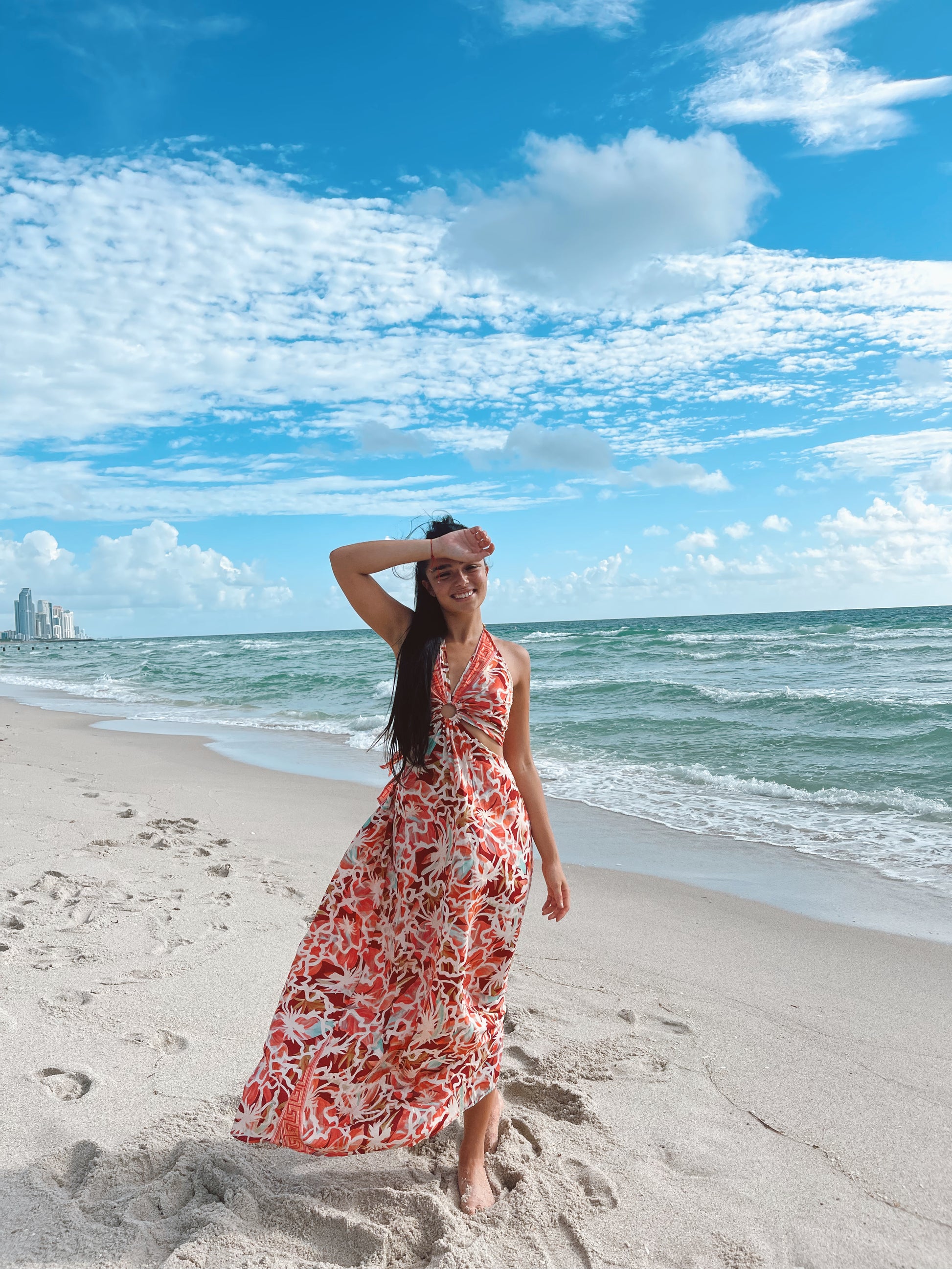 Front view of model on the beach wearing a multicolor silk maxi dress, one size, with open back tie