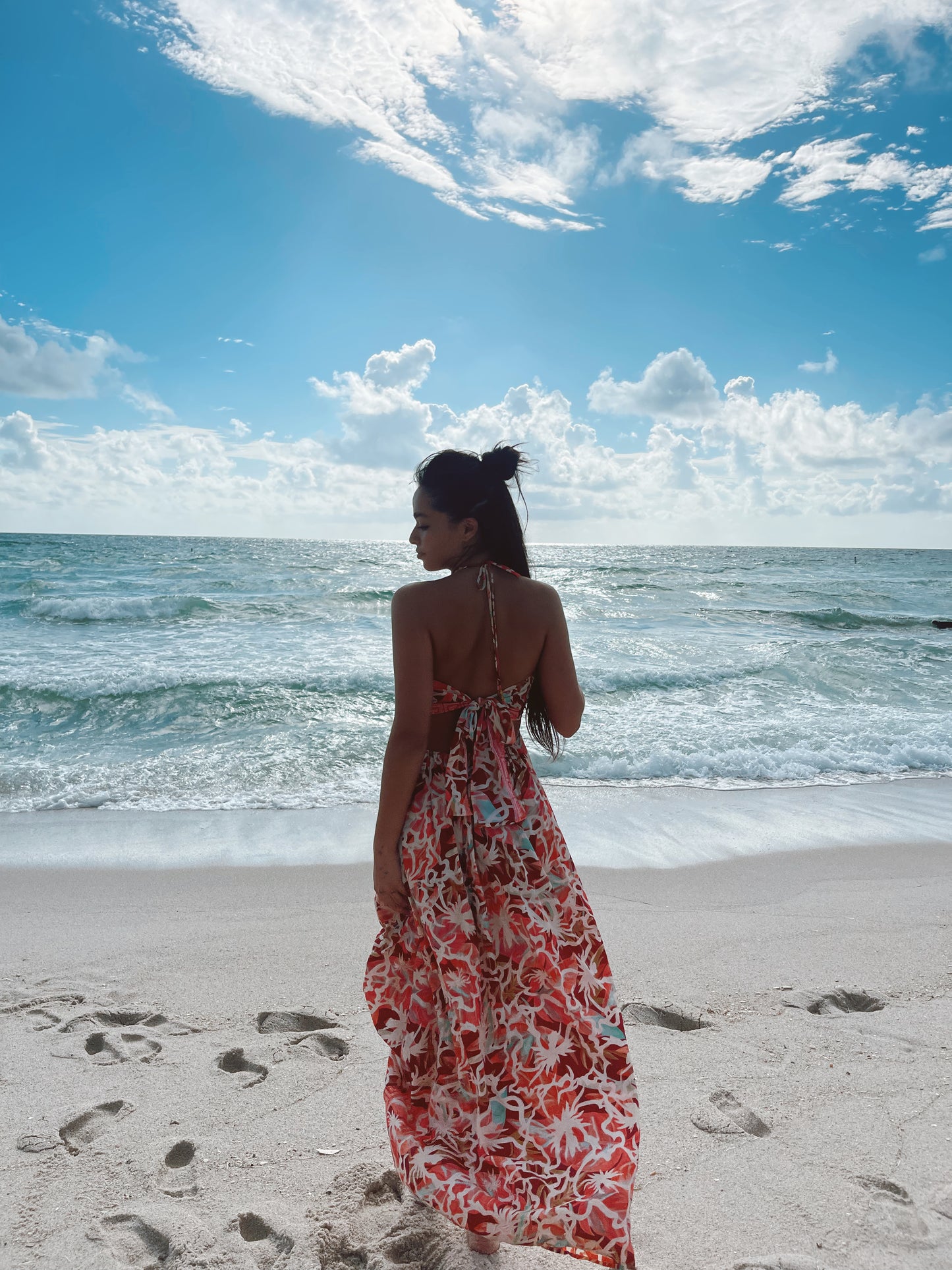 Back view of model at the beach wearing a multicolor silk maxi dress with open back tie