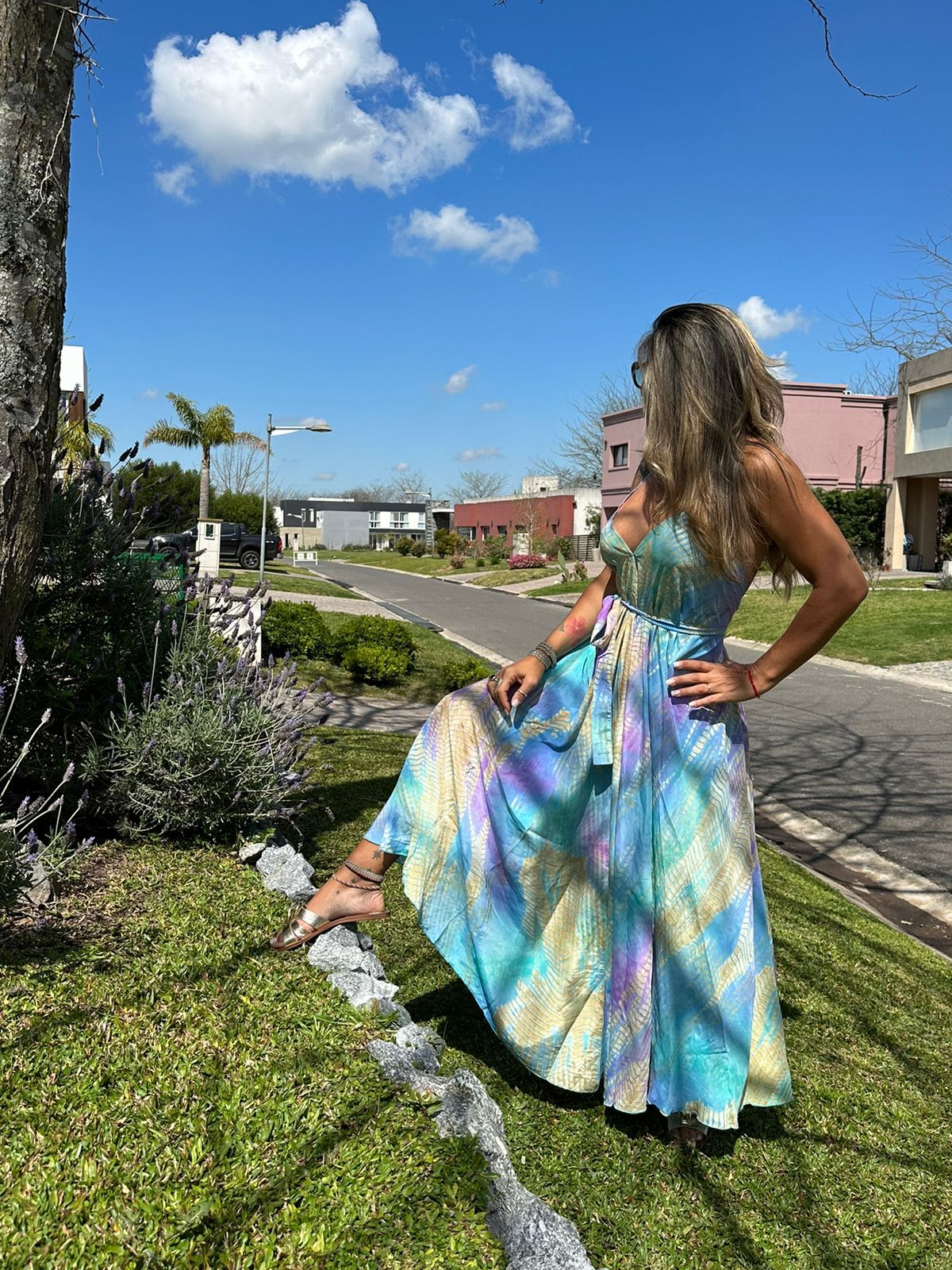 MODELO CON PIERDA  POSANDO Y MANO EN LA CINTURA CON VESTIDO LARGO MULTICOLOR