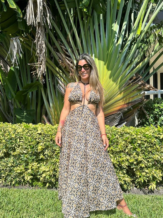 Model wearing Victoria long maxi dress with halter neck and side cutouts in a tropical garden